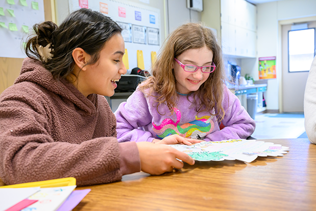 College student and elementary school student reading their pen friend letter together