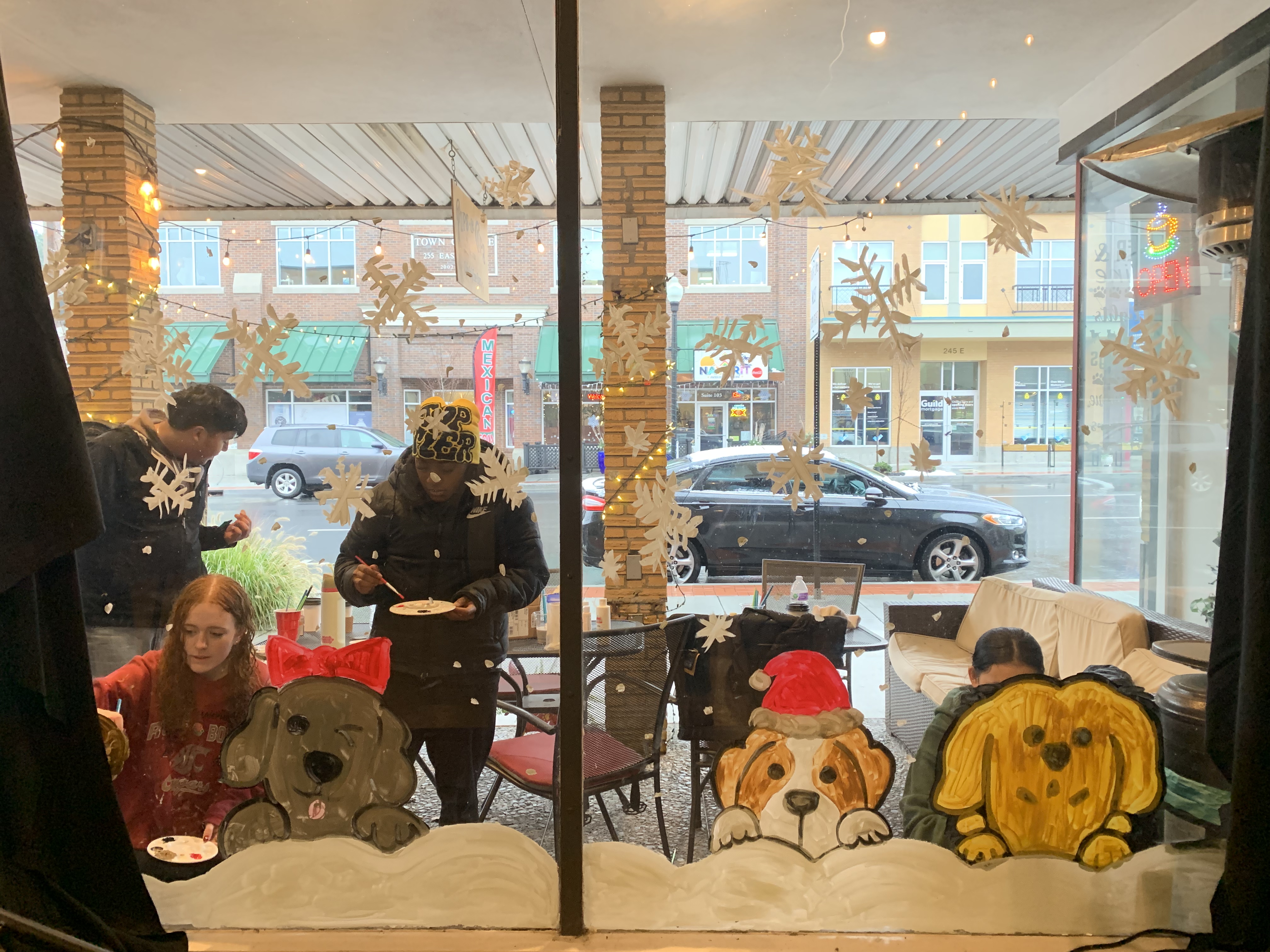 Students paint holiday images on local business window.
