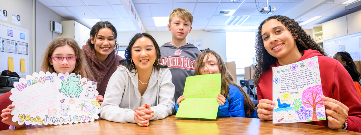Group of WSU students and elementary students holding their pen friend letters