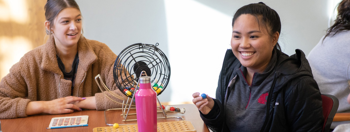 Two students working with a community partner and playing bingo